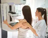 Badanie mammograficzne: co to jest? Pacjentka przygotowuje się do mammografii, a technik pomaga jej ustawić się przy aparacie.
