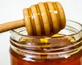 Słoik z miodem i drewniana łyżka do miodu. Naturalny antybiotyk na gardło, który pomoże złagodzić ból.