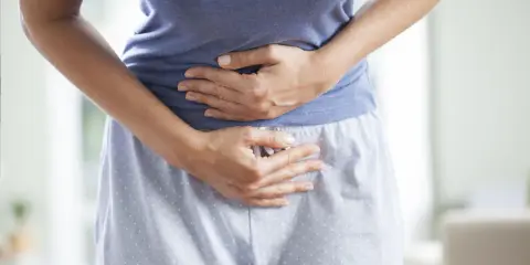 Kobieta trzyma się za brzuch, cierpiąc z powodu bólu menstruacyjnego nie do zniesienia.