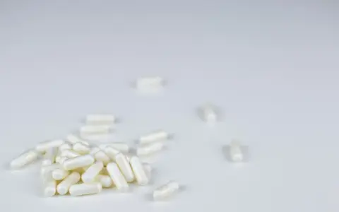 Białe kapsułki leżą na białym tle. Czy to suplement, czy anapran na co?