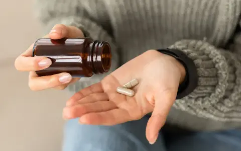 Dłoń z kapsułkami, które mogą wywołać biotyna skutki uboczne.