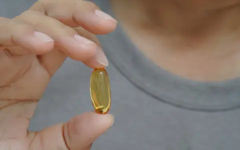 Dłoń trzyma kapsułkę z olejem. Zastanawiasz się nad omega-3 6 9 skutki uboczne?