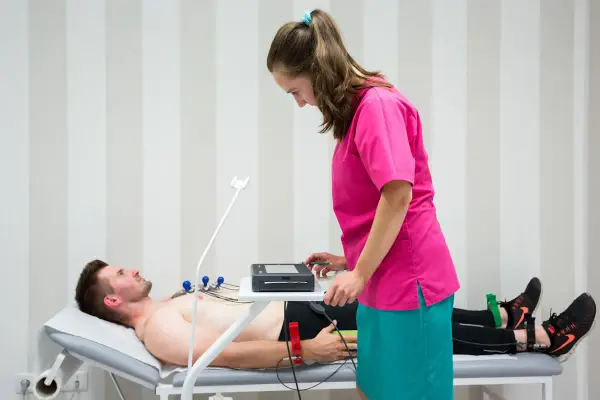 Mężczyzna leży na kozetce, pielęgniarka przygotowuje mu ekg spoczynkowe. Ile trwa badanie? Krótko, by ocenić pracę serca.